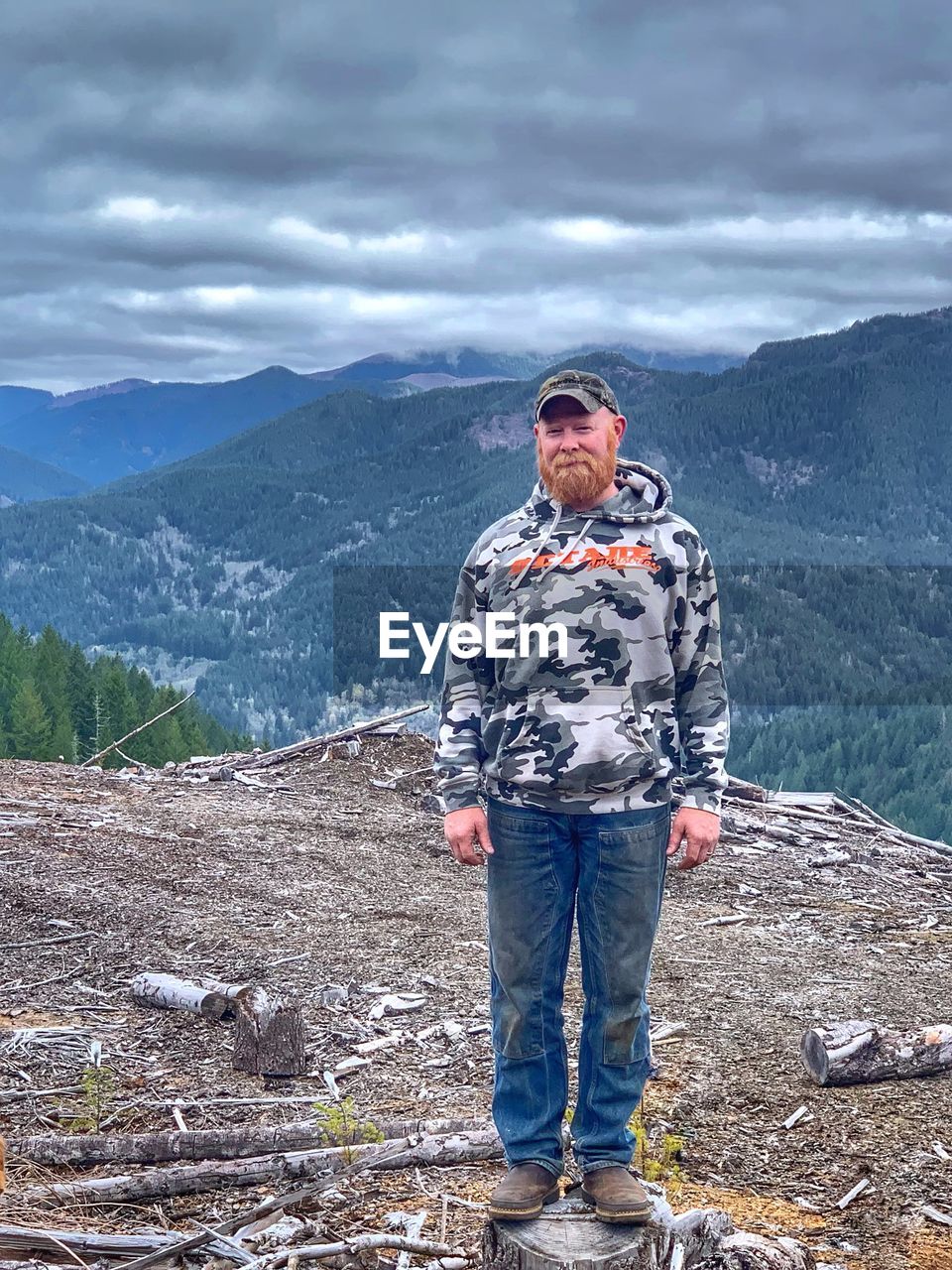 FULL LENGTH OF YOUNG MAN STANDING AGAINST MOUNTAIN RANGE