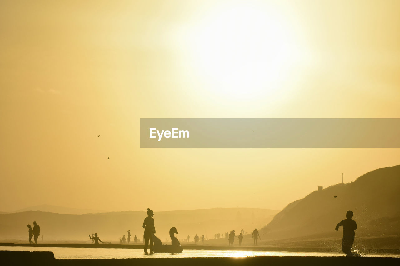 SILHOUETTE PEOPLE AT BEACH AGAINST SKY DURING SUNSET