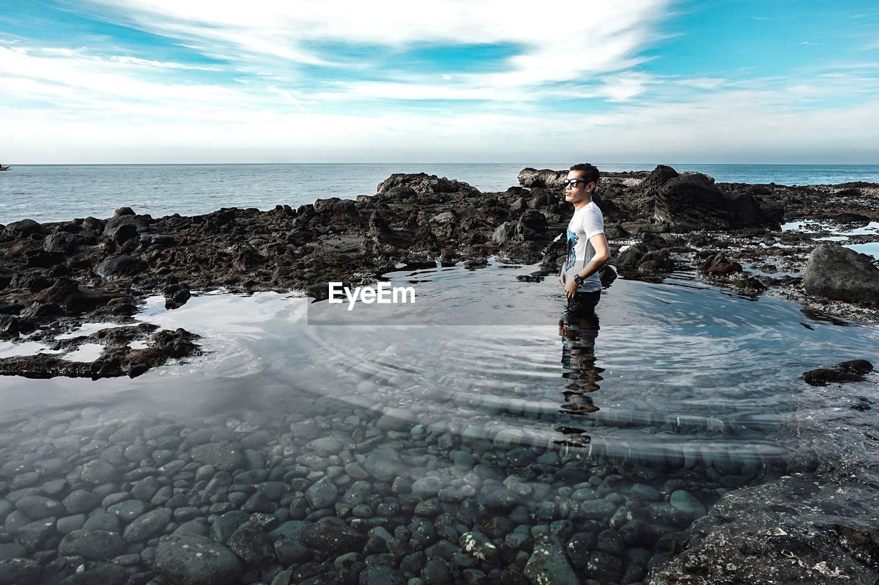 Man standing in sea against sky