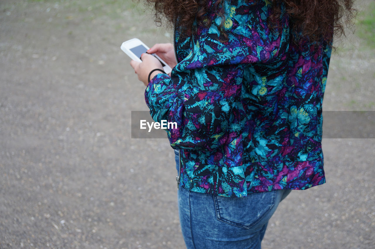 Midsection of woman using mobile phone while standing on street