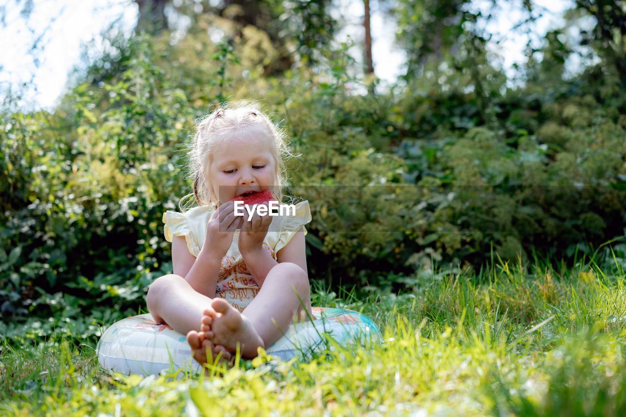 Cute caucasian girl eating watermelon in countryside