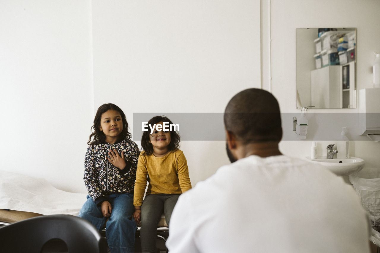 Girls looking at male doctor in medical clinic