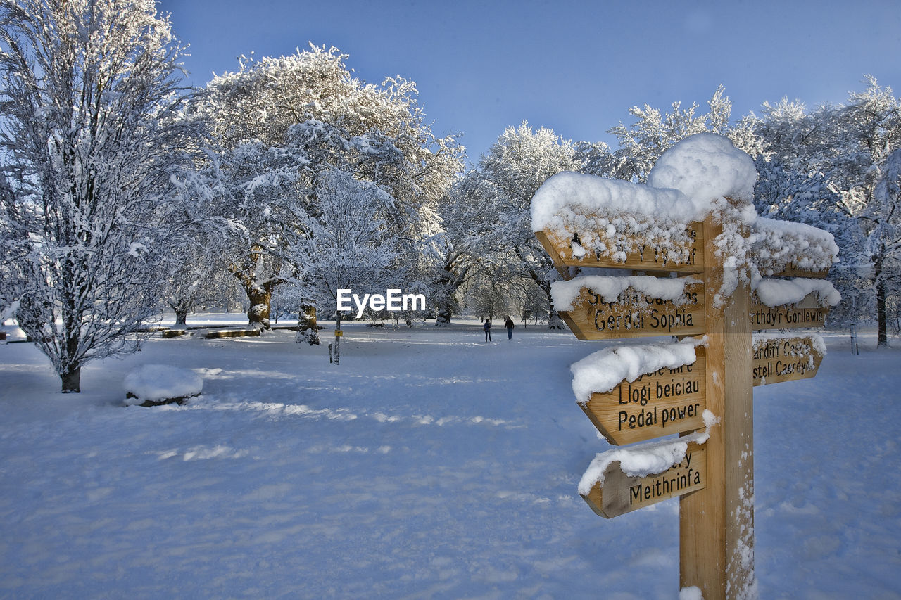 Wooden directional sign on snow covered field