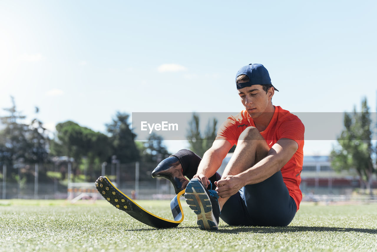 Man with prostethic leg sitting and tying shoes