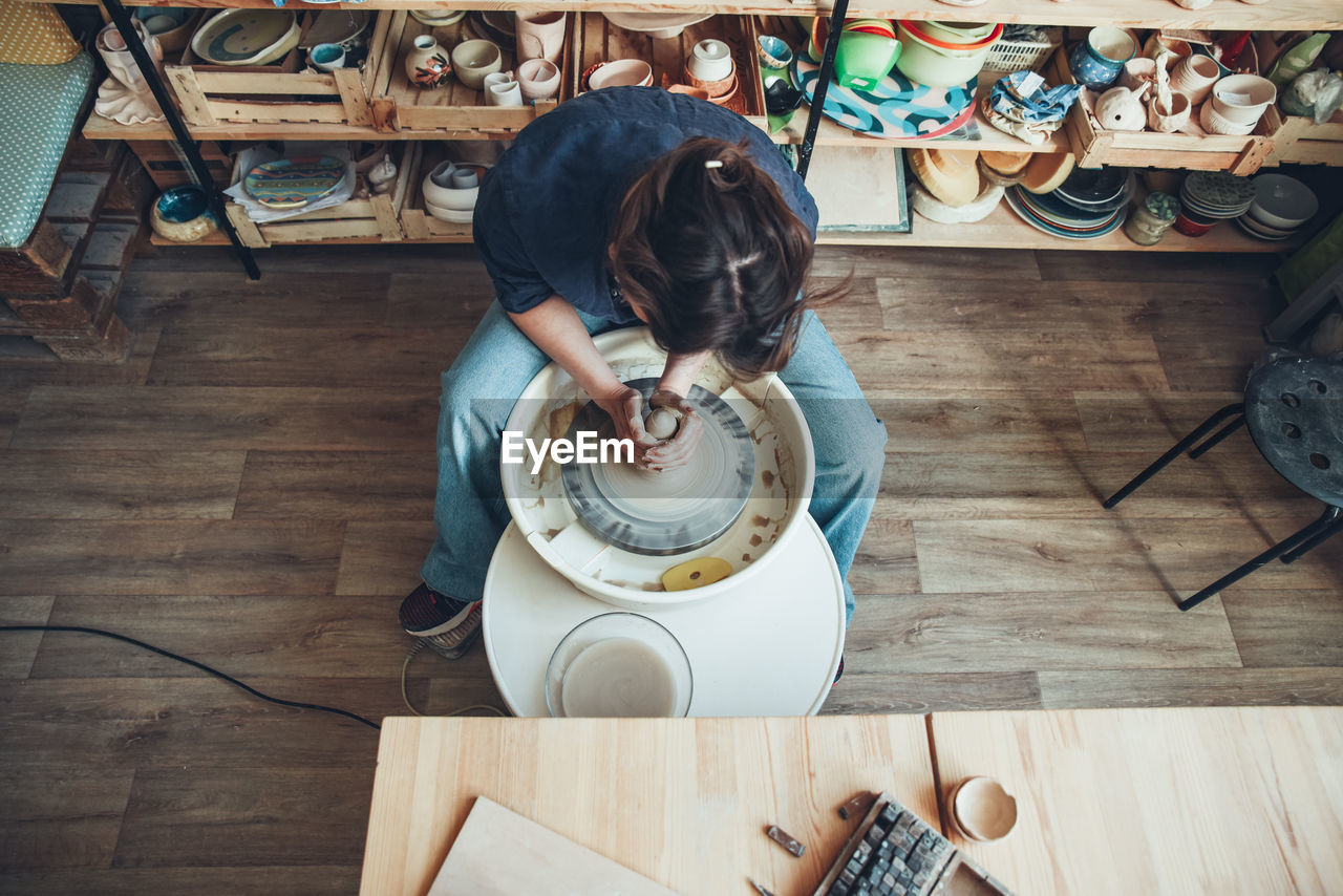 A woman ceramist at a pottery wheel in a workshop