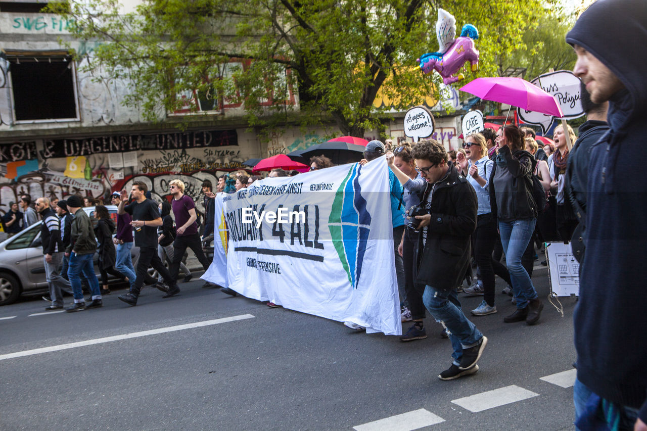 Crowd walking on street by buildings at may day