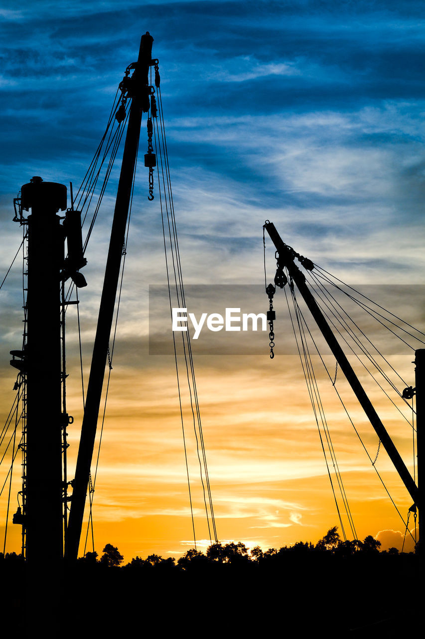 Silhouette cranes against sky during sunset