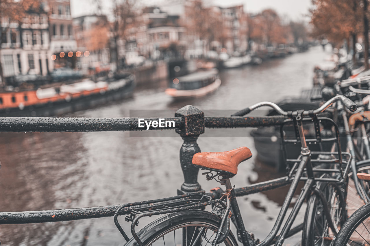 Close-up of bicycle by canal and buildings