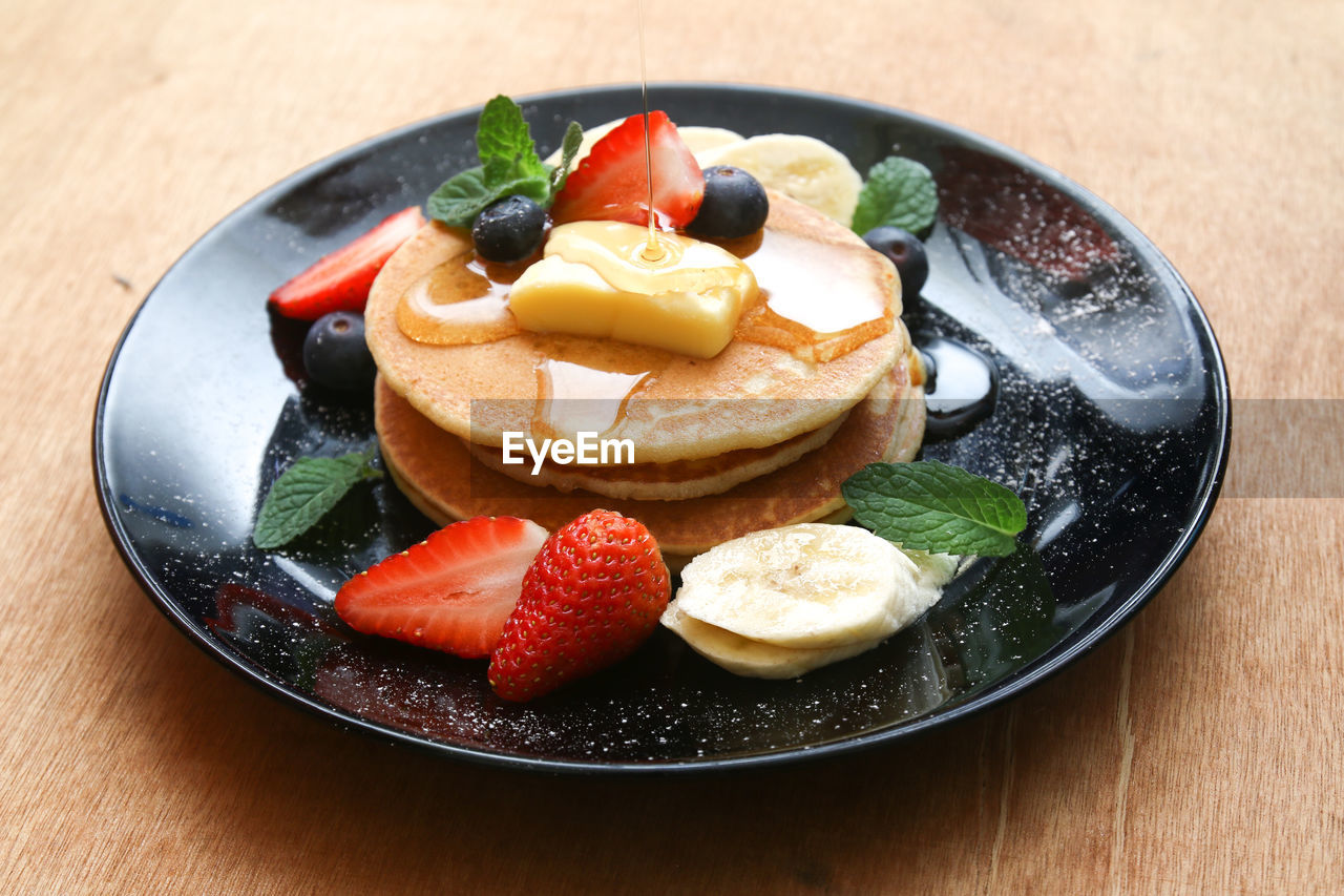 CLOSE-UP OF FRUITS IN PLATE WITH STRAWBERRIES ON TABLE