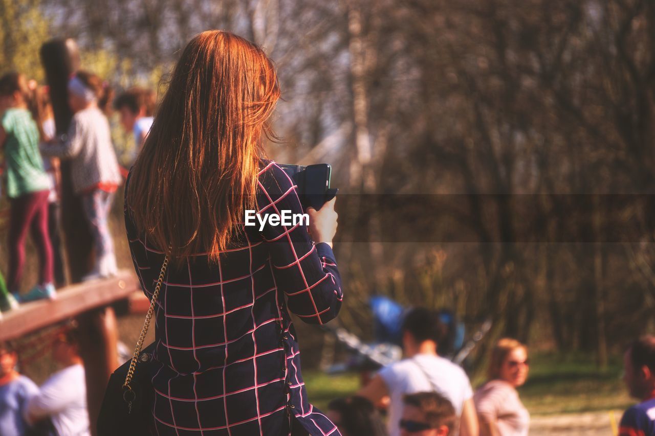 Rear view of woman photographing outdoors