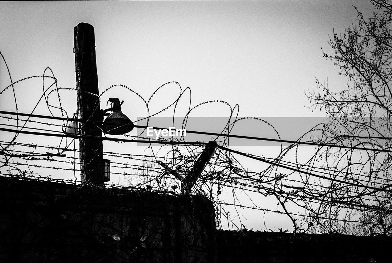 Low angle view of barbed wire fence against sky