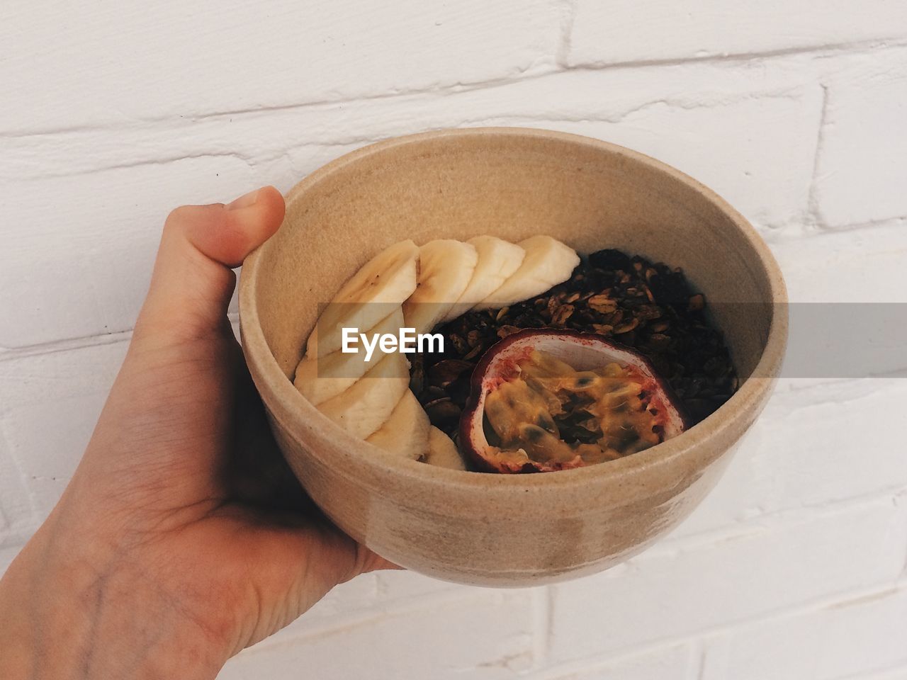 CLOSE-UP OF HAND HOLDING BOWL OF NOODLES