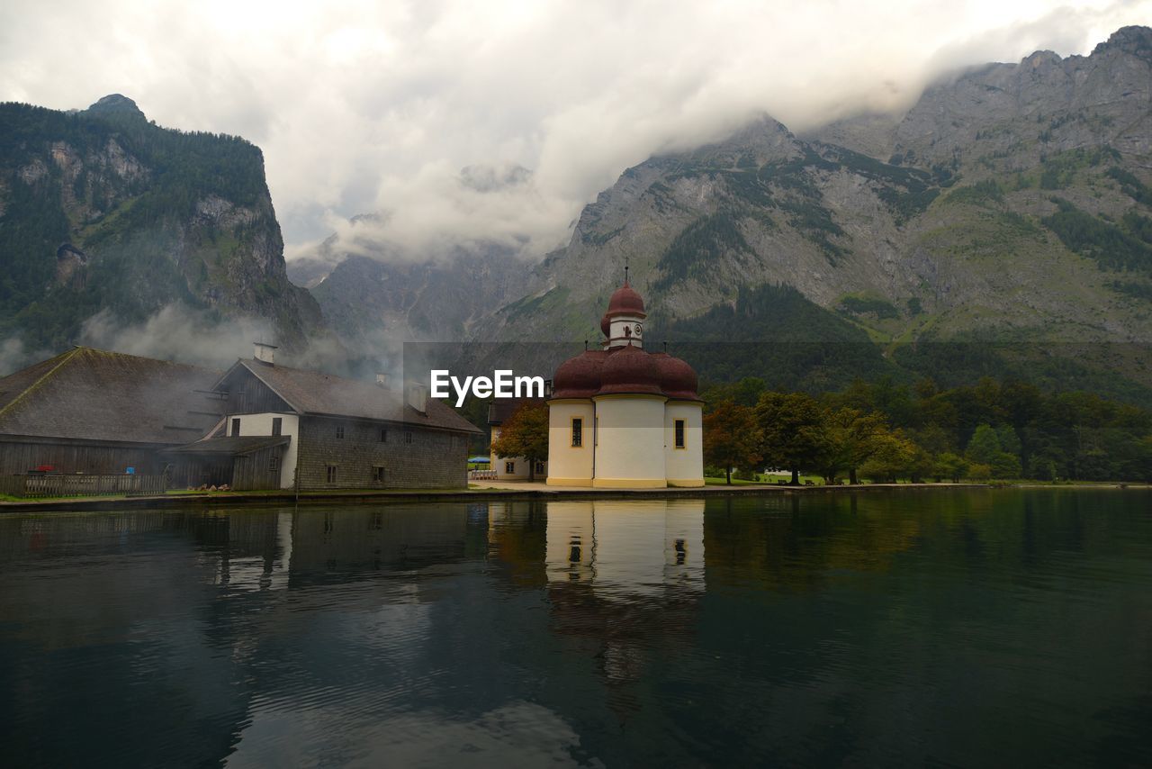 St bartholomews church by calm lake against mountain