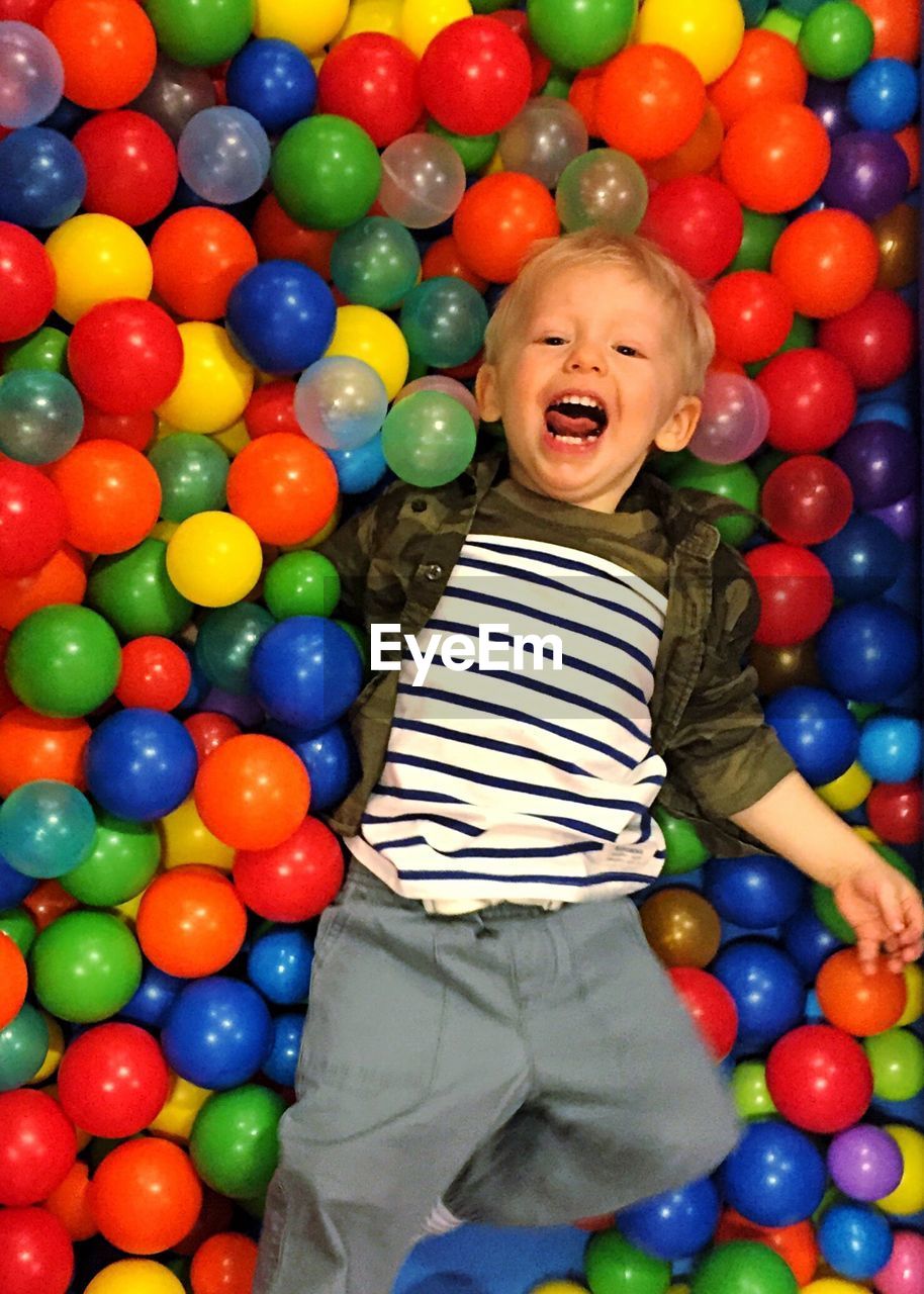 High angle view of cheerful boy in ball pool