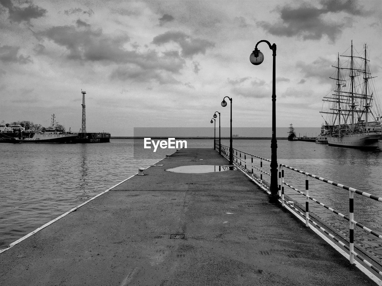 Pier on calm sea against cloudy sky