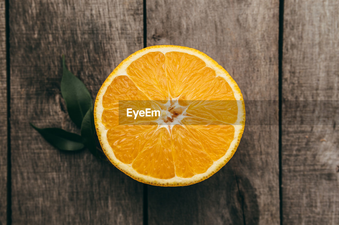 Sliced halves of orange fruit on gray wooden background. pulp and green leaves. high quality photo