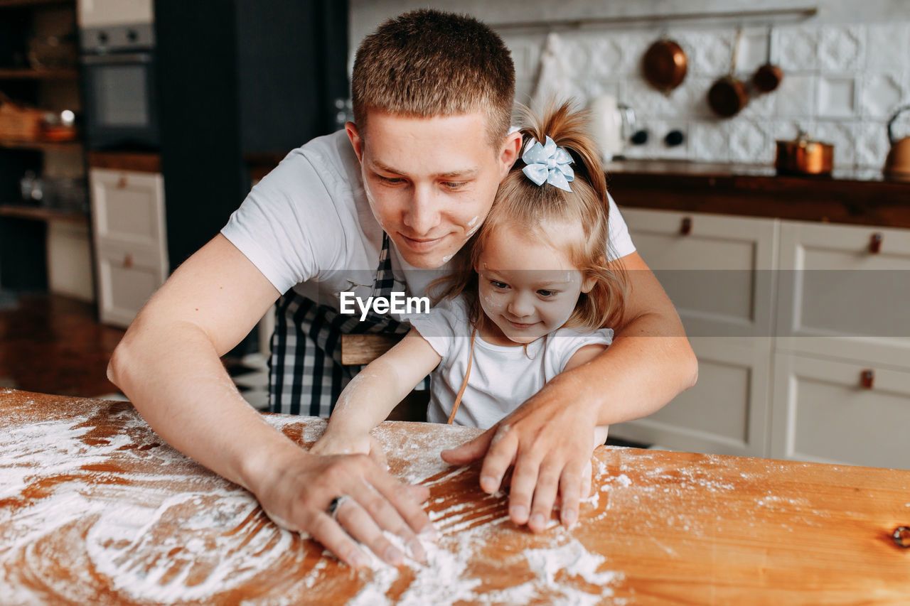 Funny happy dad and daughter baby cook together fool around and play with flour in  kitchen at home