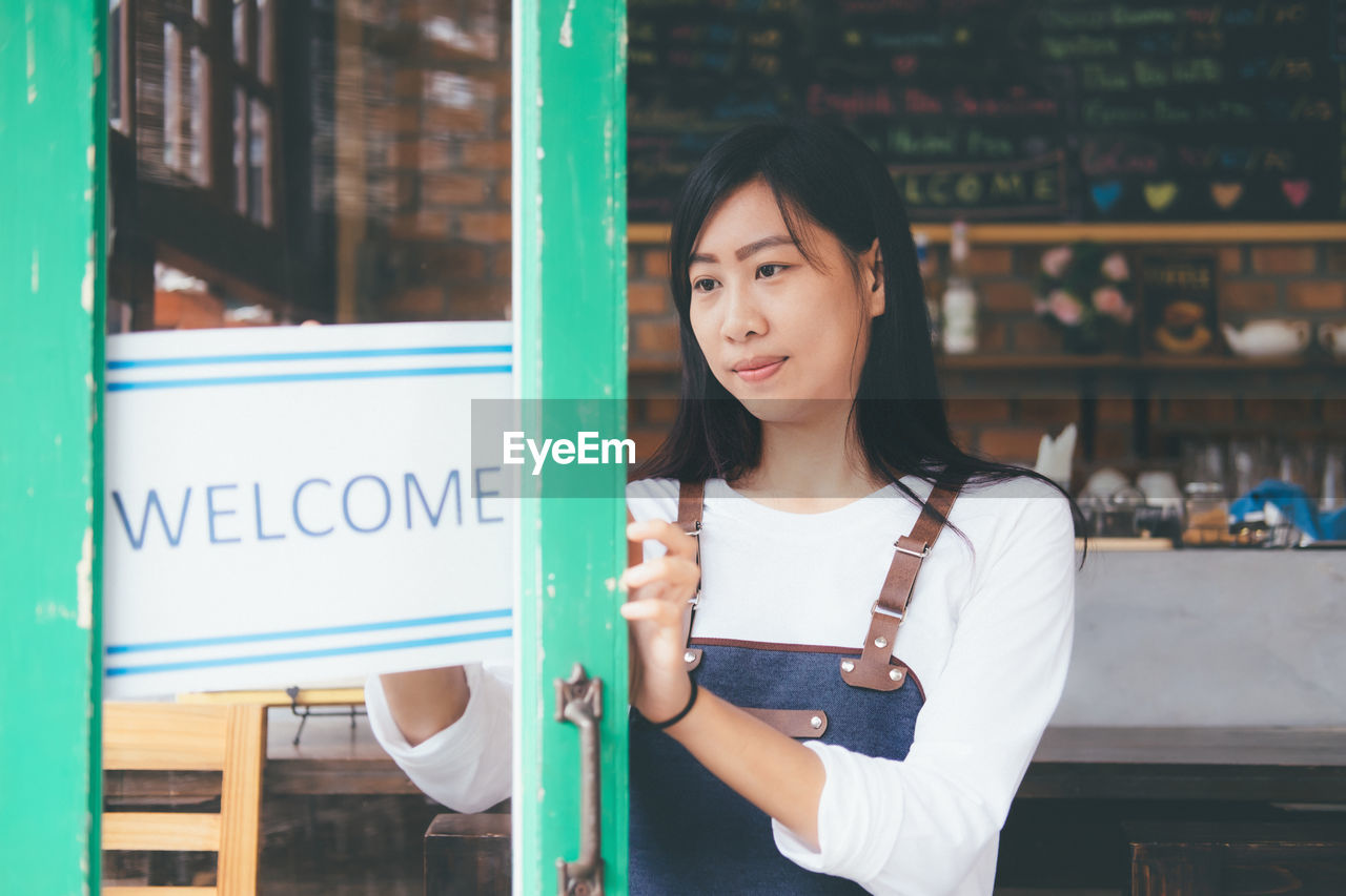 Owner with welcome sign standing in store