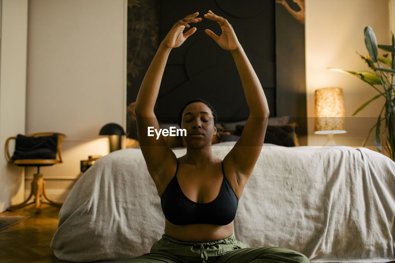 Young woman practicing breathing exercise in bedroom at home