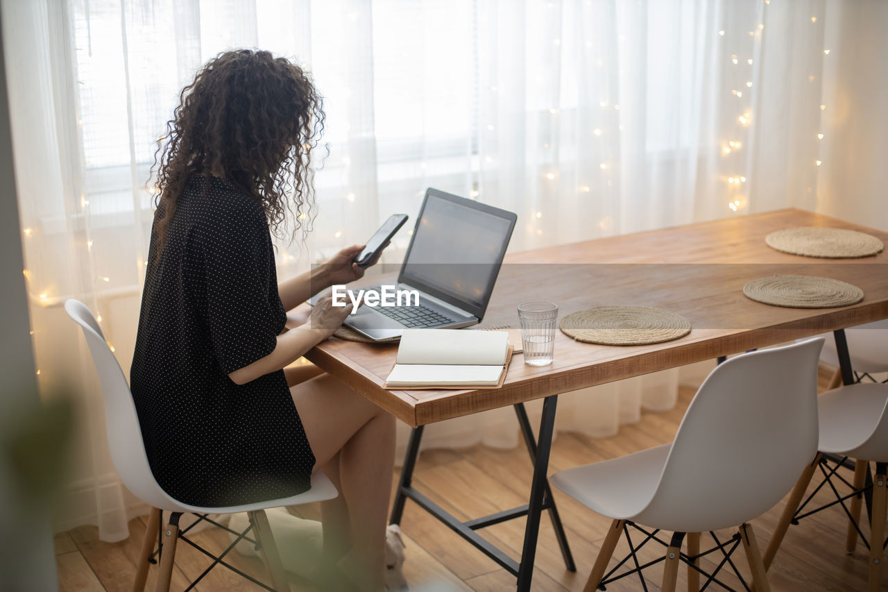 Rear view of woman using laptop on table