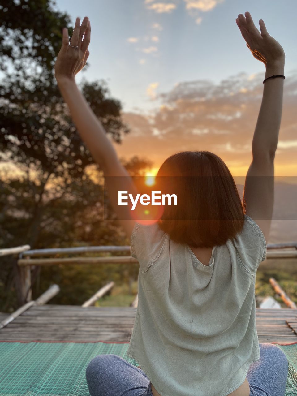 REAR VIEW OF WOMAN WITH ARMS RAISED AGAINST SKY