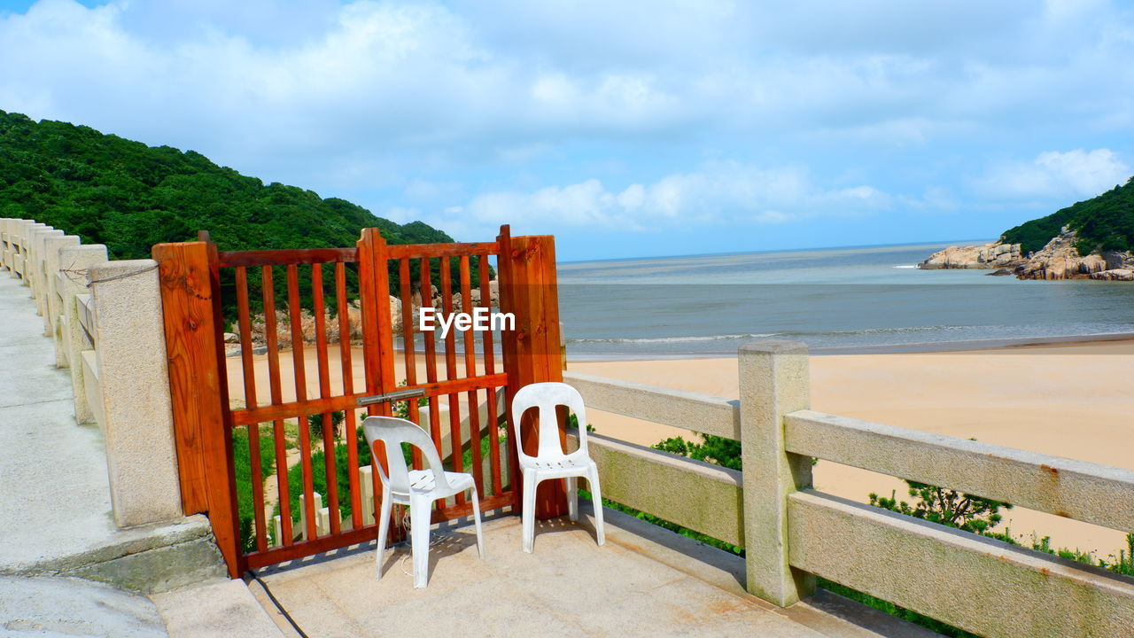 Chairs and table at beach against sky