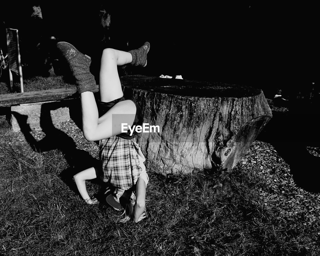 Mid adult woman doing headstand on grassy field at night