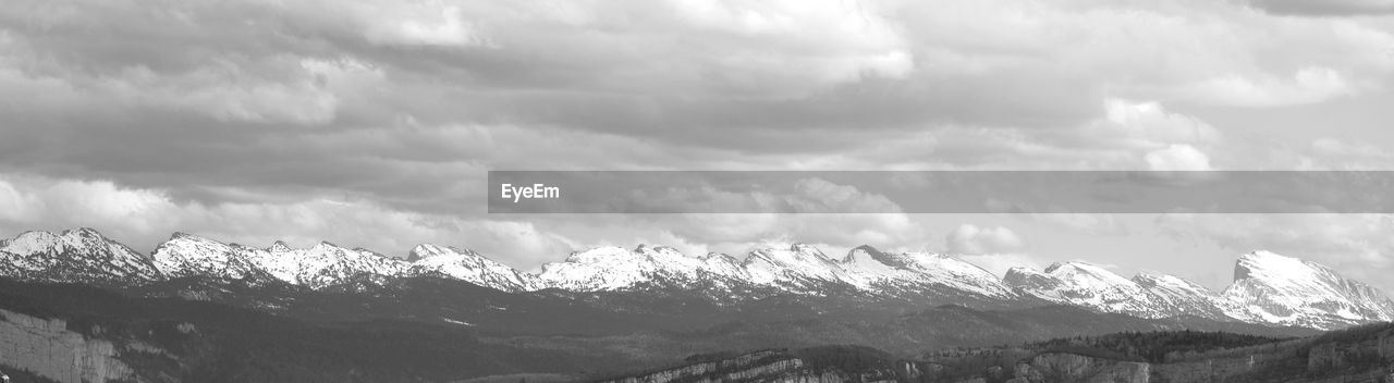 SNOW COVERED MOUNTAINS AGAINST CLOUDY SKY