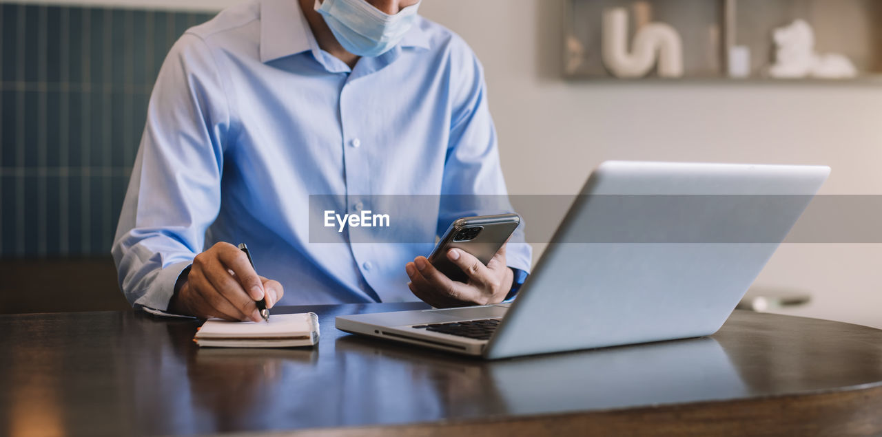 midsection of woman using mobile phone while sitting at table