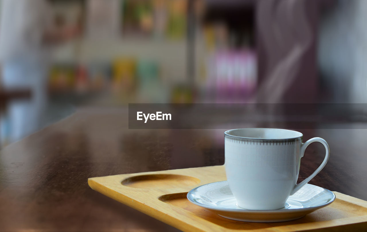 mug, drink, cup, coffee cup, coffee, food and drink, table, refreshment, saucer, crockery, cafe, hot drink, indoors, focus on foreground, business, coffee shop, kitchen utensil, selective focus, wood, tea, coffee break, close-up, spoon, day, relaxation, lifestyles, restaurant, freshness, tea cup, food, eating utensil, still life, no people, morning