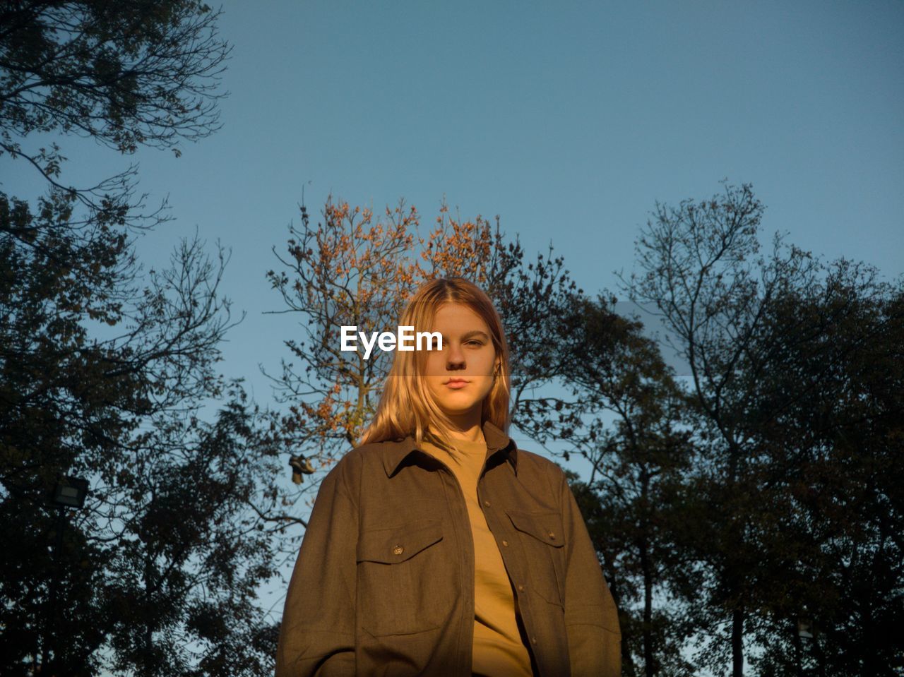 Portrait of smiling woman standing against trees and sky