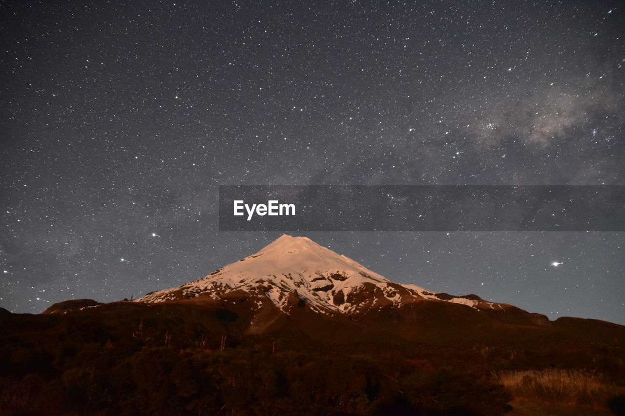 SCENIC VIEW OF MOUNTAINS AGAINST STAR FIELD AGAINST SKY