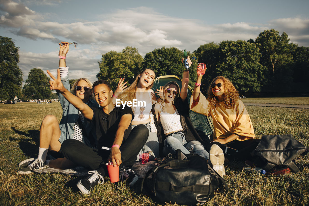 Happy young friends enjoying while sitting on grass at music concert