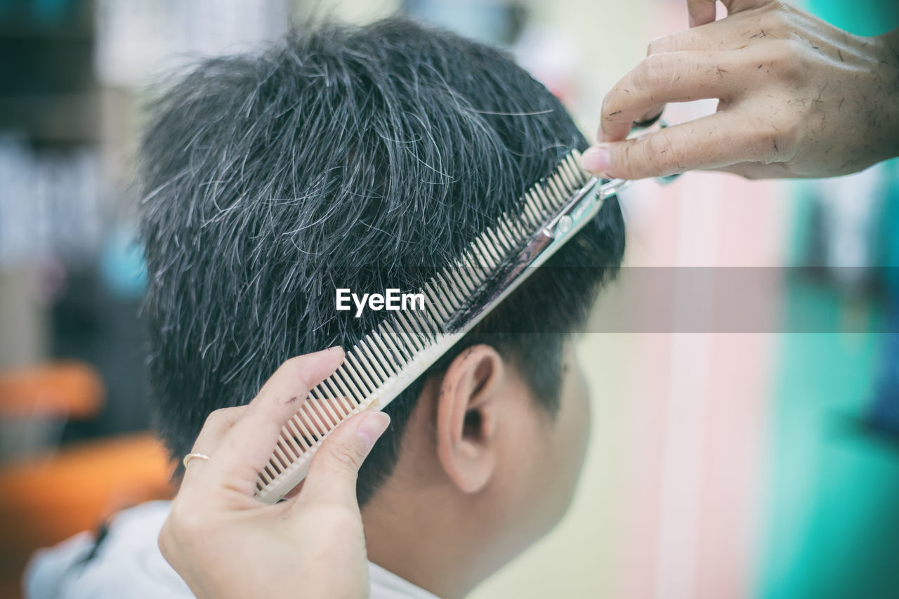 Close-up of barber cutting hair of customer