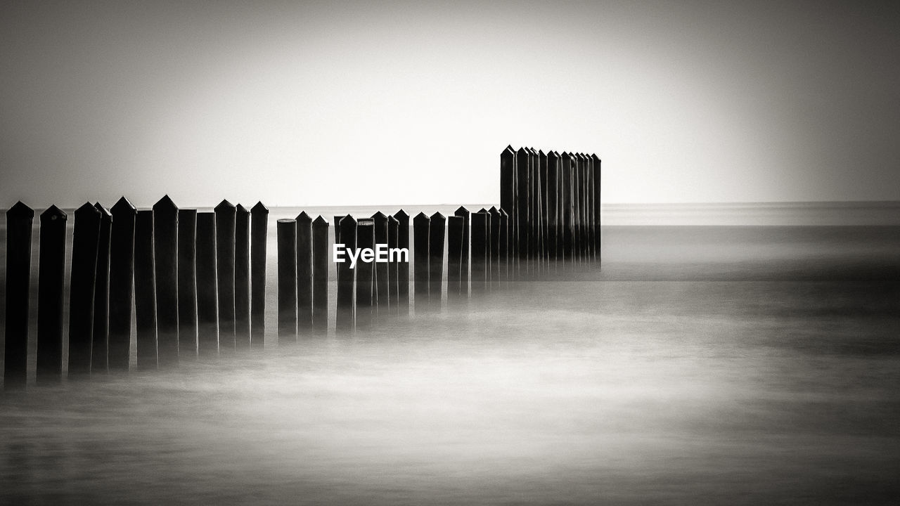WOODEN POSTS IN SEA AGAINST SKY