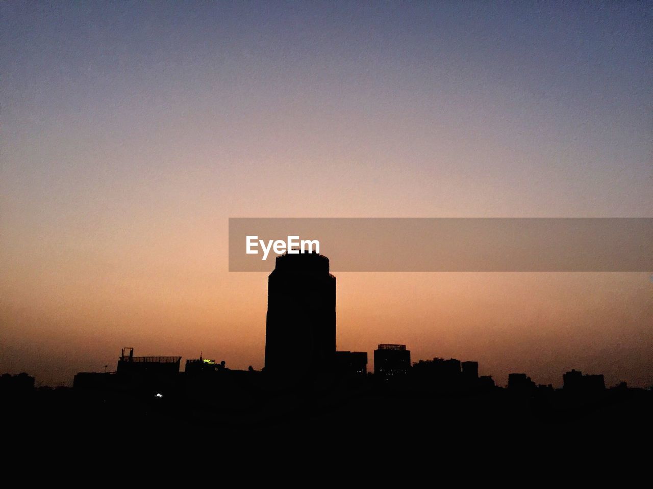 SILHOUETTE OF BUILDINGS IN CITY AT SUNSET