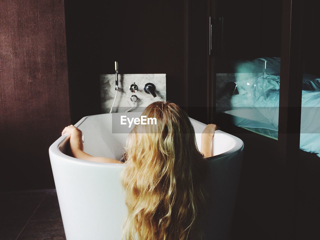 Rear view of woman sitting in bathtub