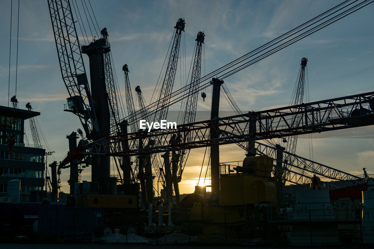 LOW ANGLE VIEW OF CRANES AT CONSTRUCTION SITE