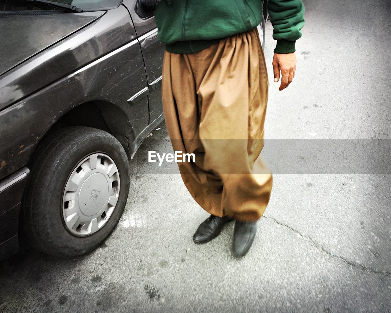 Low section of man walking by car