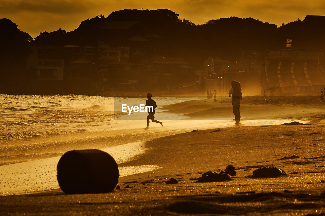 Silhouette of people on beach at sunset