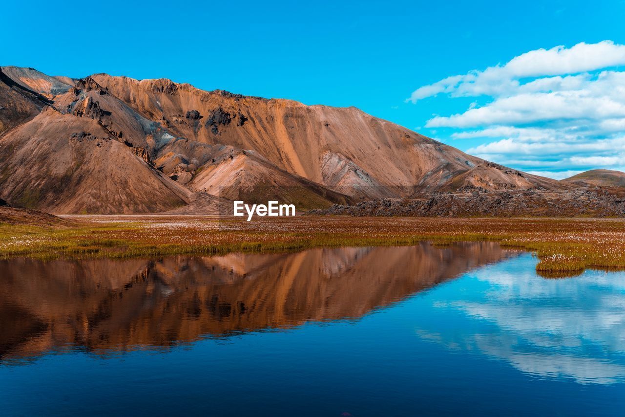 Scenic view of lake and mountains against blue sky