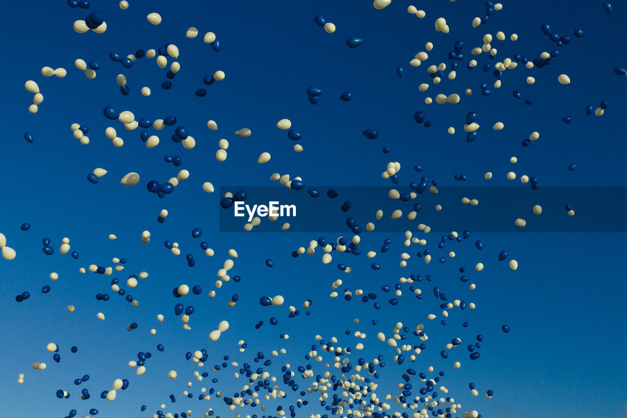Low angle view of balloons flying against clear blue sky
