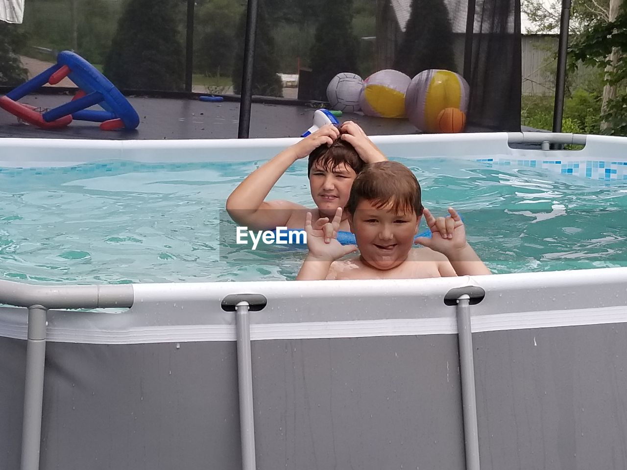 PORTRAIT OF HAPPY BOY WITH SWIMMING POOL