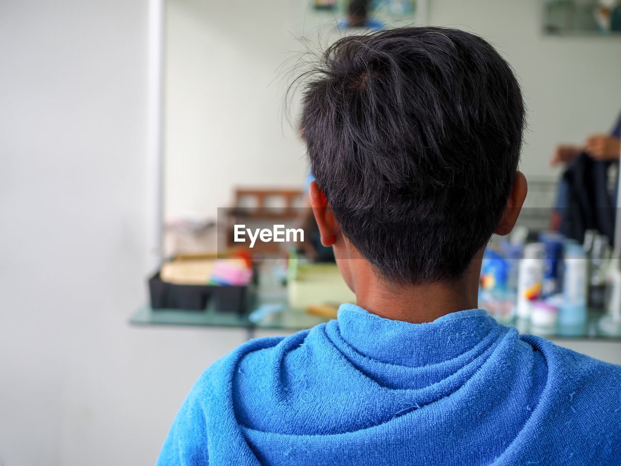 Rear view of man wrapped in blue towel at barber shop