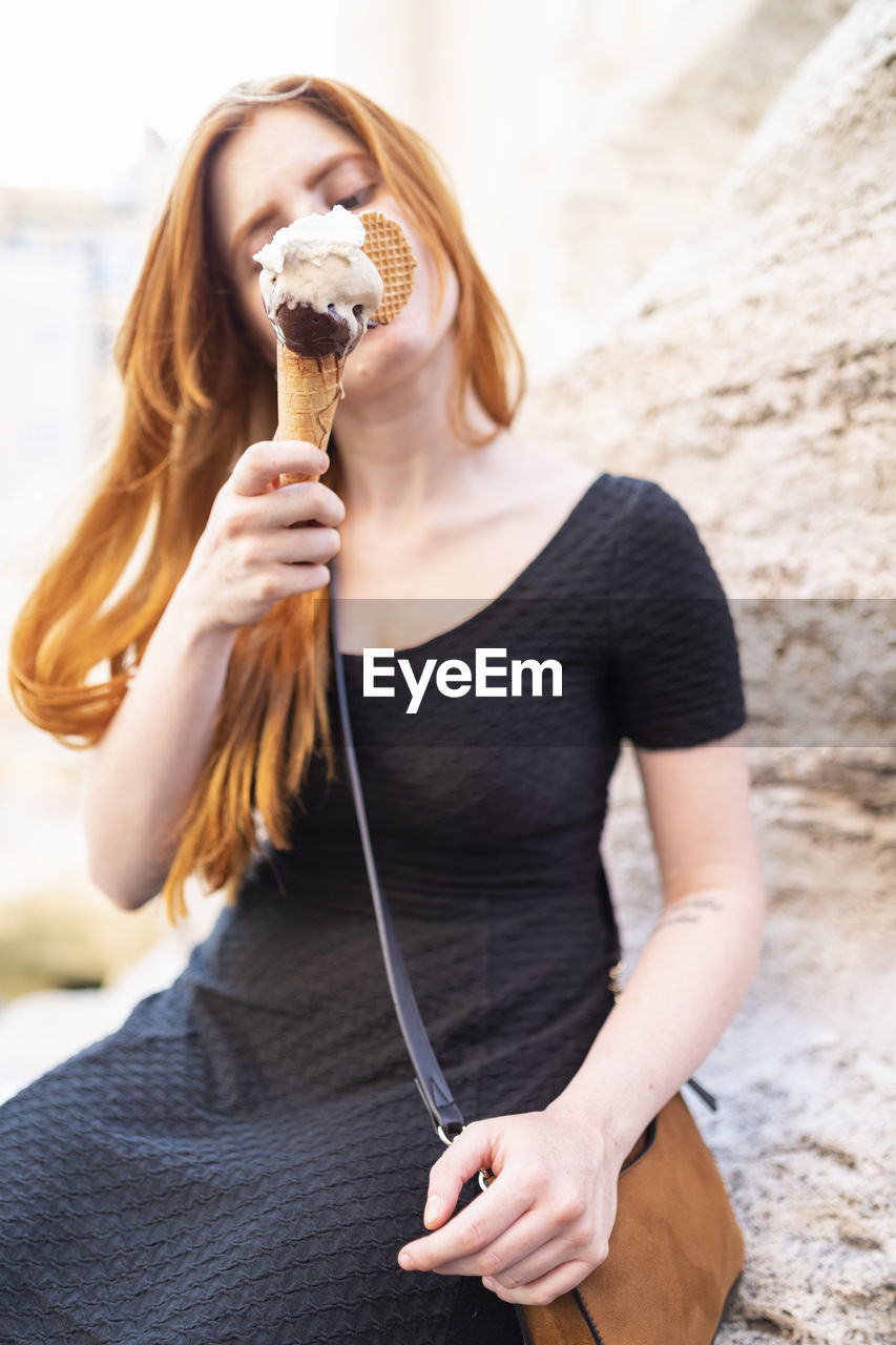 Young redhead woman refreshing with ice cream