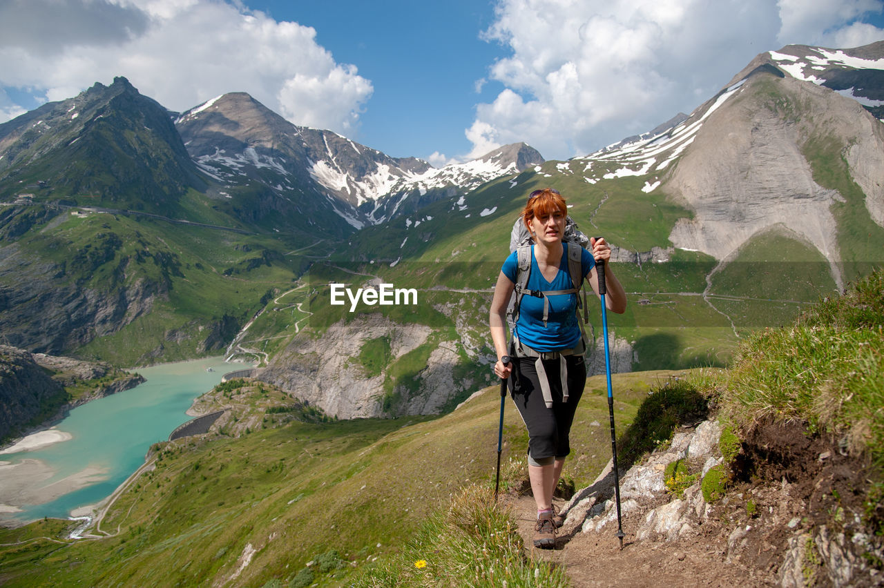 Full length of woman hiking on mountain against sky