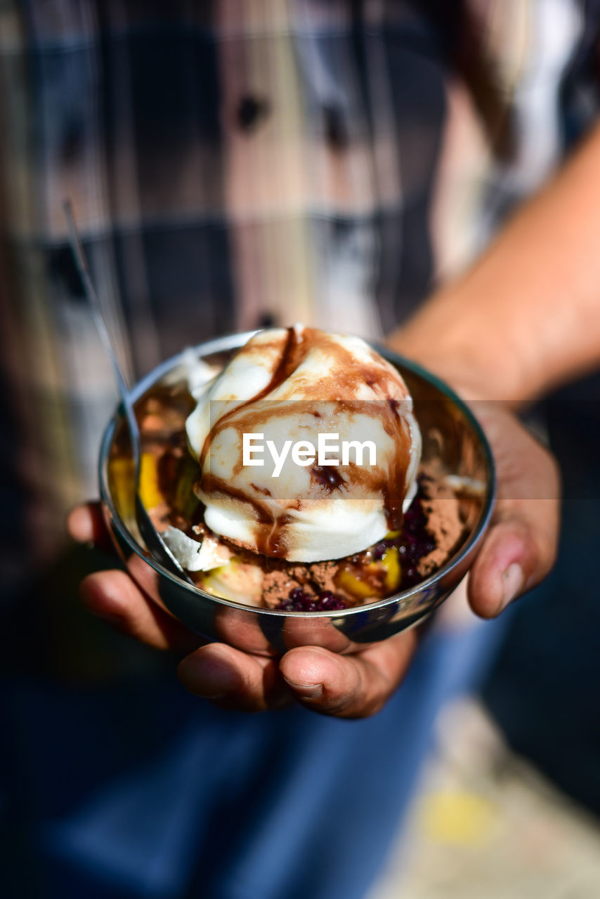 Midsection of man holding ice cream in bowl