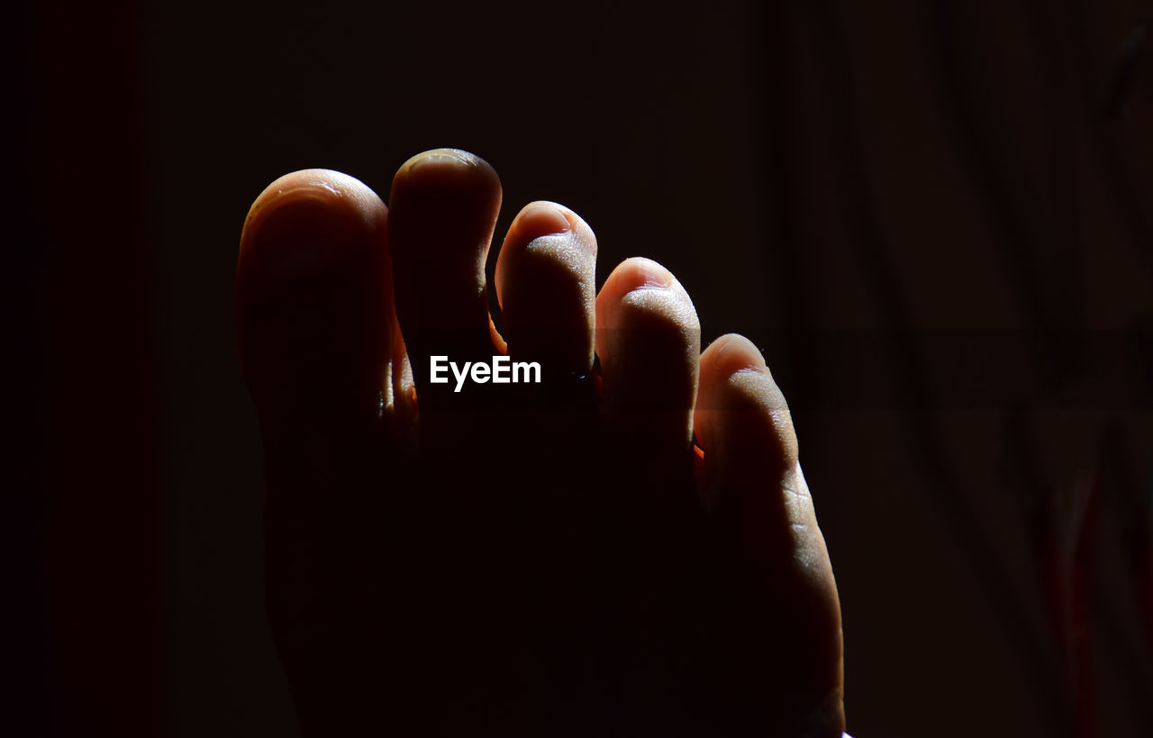 Close-up of human foot against black background