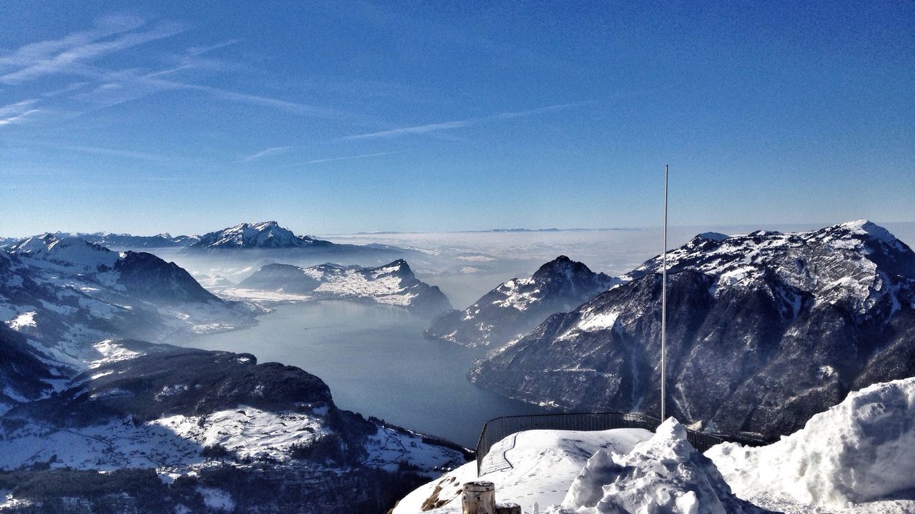 High angle view of snow covered mountains against blue sky