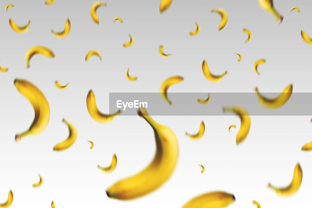 Full frame shot of bananas in mid-air over white background